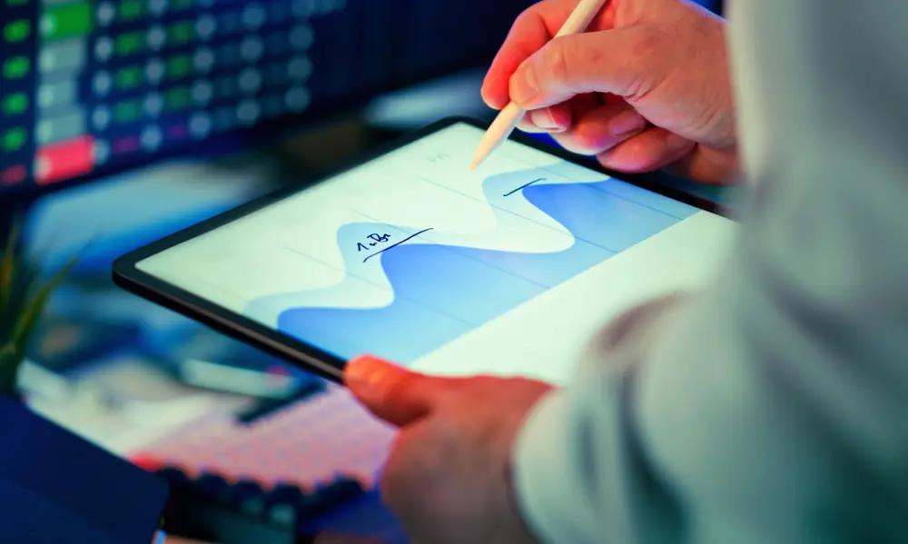 Hand on a tablet showing a bar chart
